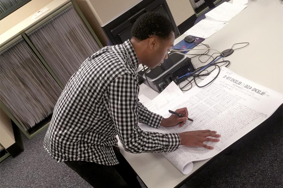 A person leans over a large sheet of paper in the Milwaukee County Deeds Office.