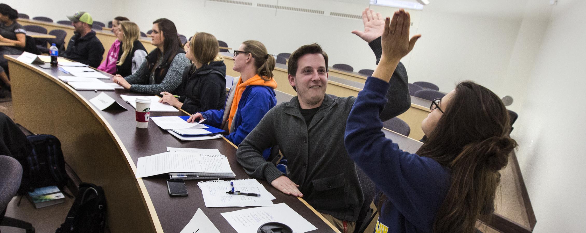 Two students high five in a classroom.