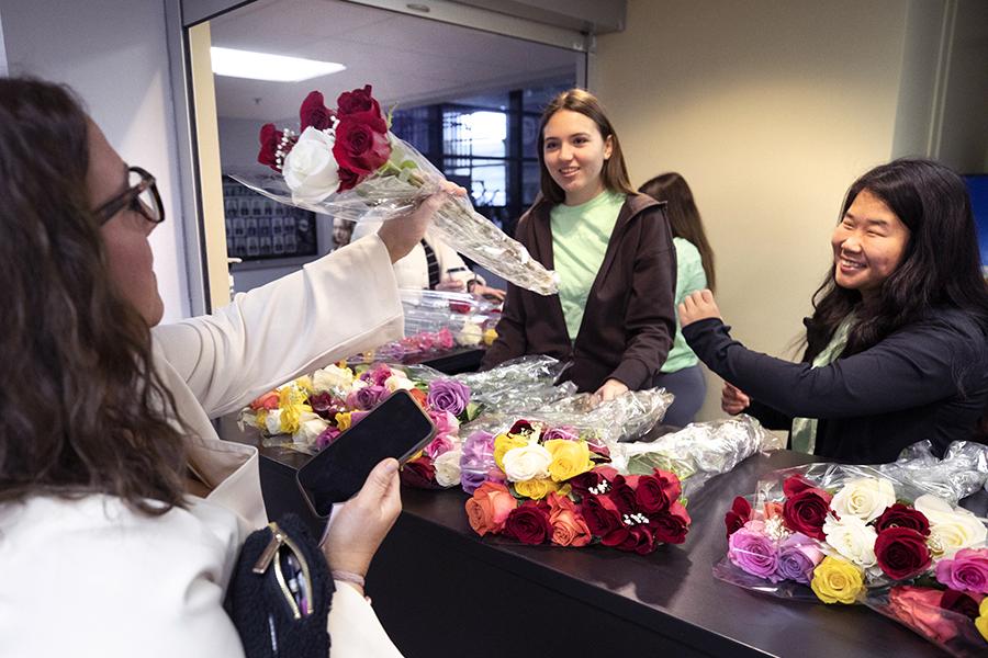 Students sell flowers behind a counter.