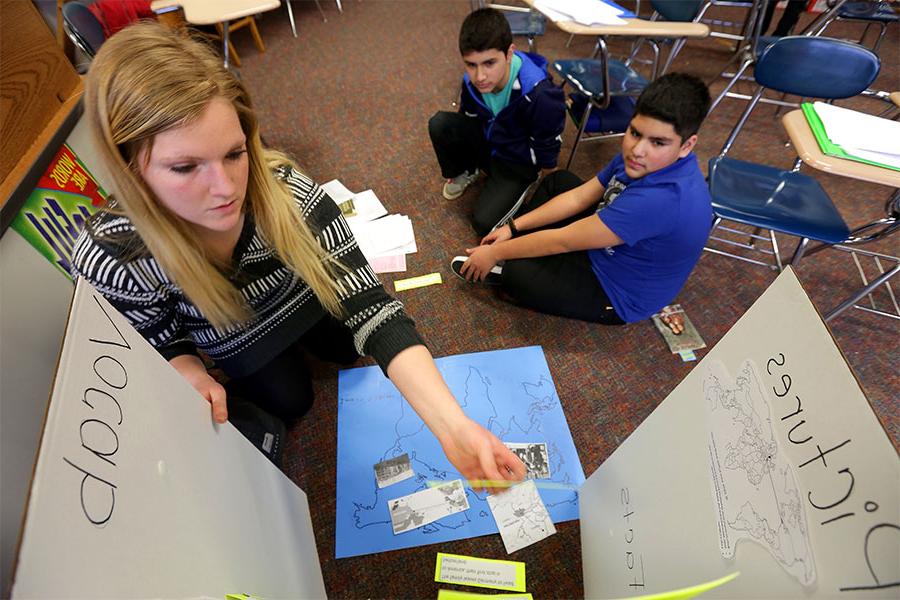 Middle school teacher teaches lesson to two students