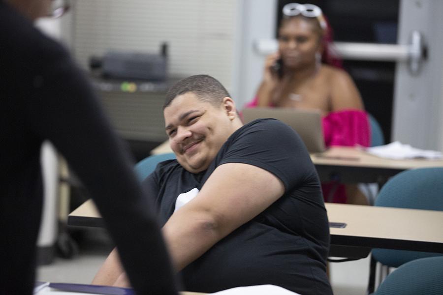 A student sits in class, smiling.