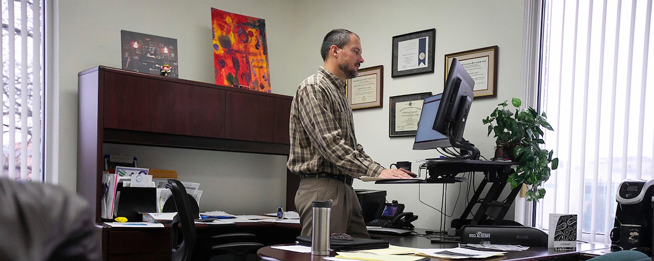 Man standing in front of standing desk working on computer.