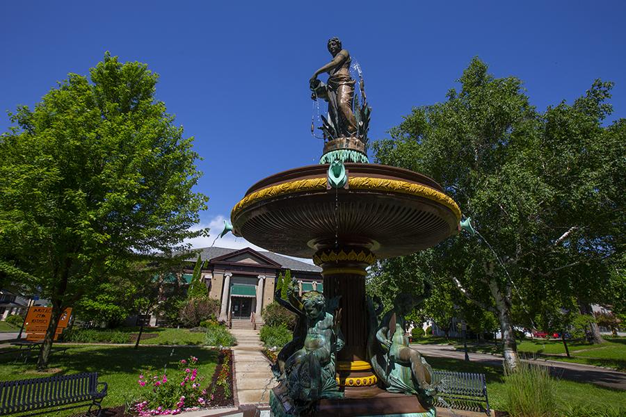 A two tier fountain in downtown Whitewater surrounded by trees.