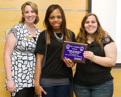 Group of students posing for a picture and holding a plaque