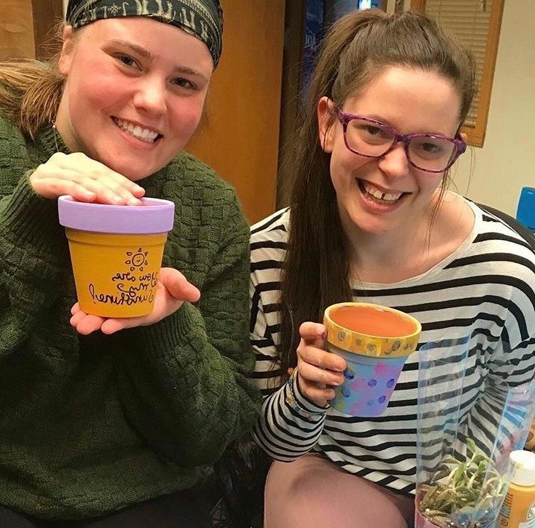 Two residents holding painted garden pots at a sustainability program