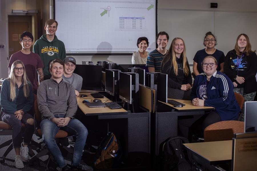 Students gathered in a classroom smile at the camera.