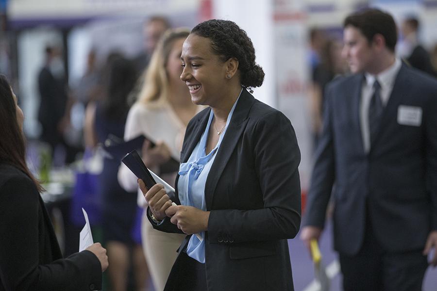 Smiling student holding binder at Hawk Career Fair